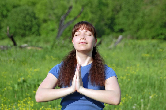 年輕快樂女子在綠色草地上練習(xí)瑜伽