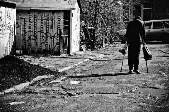 一个生病的穷人拄着拐杖走在街上