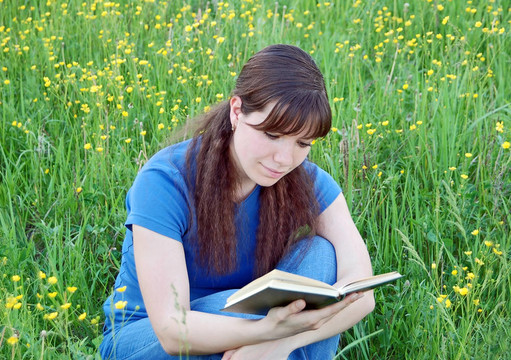 年輕女子在草地上看書