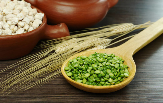 綠色的豌豆豌豆在作物和碗在背景（選擇性重點(diǎn)；重點(diǎn)綠色豌豆和前面的勺子）