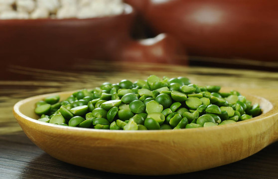 綠色的豌豆豌豆在作物和碗在背景（選擇性重點(diǎn)；重點(diǎn)綠色豌豆）