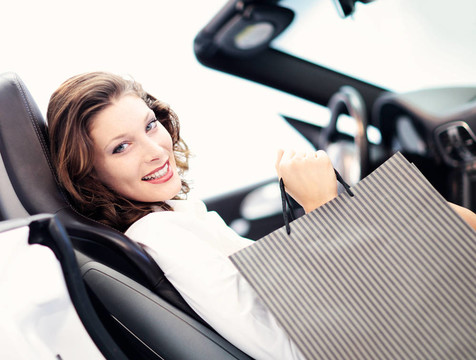 迷人的女人在車與購物袋