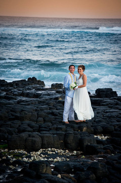 剛剛結(jié)婚。美麗的年輕夫婦在巖石海岸。