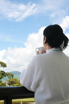 專業(yè)的商人帶浴室的衣服抱著咖啡杯，一個(gè)美麗的風(fēng)景若有所思