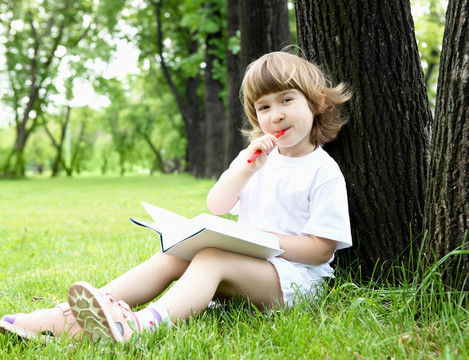 小女孩在公園里看書的畫像