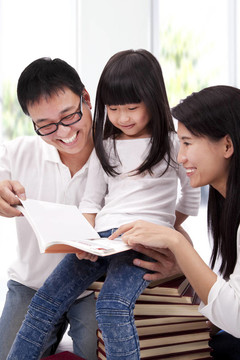 快樂(lè)亞洲家庭一起學(xué)習(xí)。家長(zhǎng)幫助女兒閱讀書(shū)
