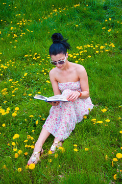 年輕的女人在公園里讀一本書