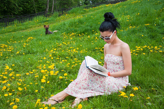 年輕的女人在公園里讀一本書