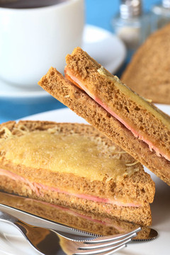 Croque Monsieur。烤全麥面包三文治火腿奶酪和磨碎的奶酪在上面切成兩半躺在彼此（選擇性聚