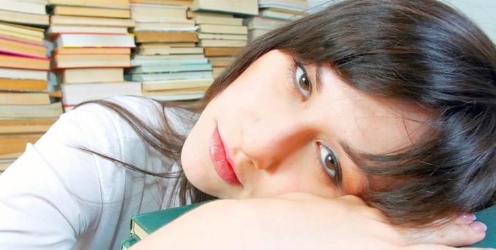 漂亮的年輕學(xué)生女孩幾乎在她的書上睡著了