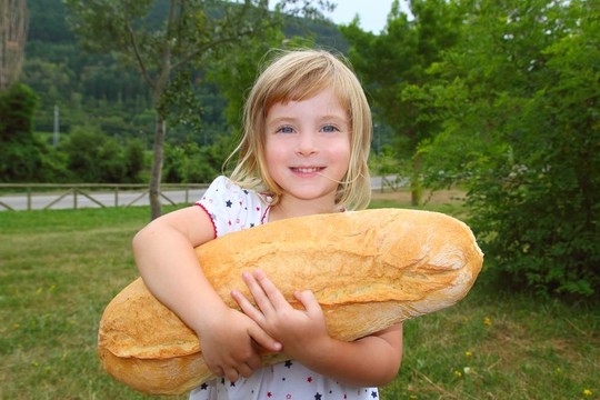 女孩抱著大面包的幽默大小饑餓的孩子