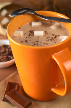 与对侧边和巧克力片一茶匙橙杯棉花糖热巧克力（选择性聚焦；在热巧克力中的棉花糖的重点）