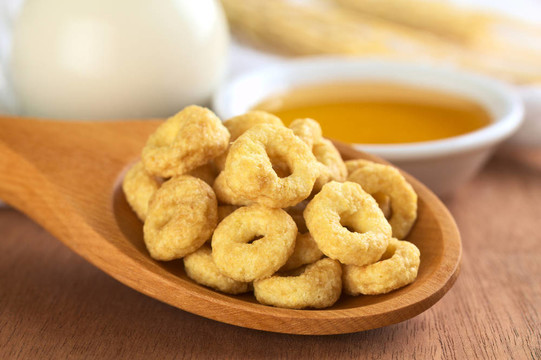 蜂蜜味麥片圈后面有牛奶和蜂蜜的木勺子（選擇性聚焦；在前面上循環(huán)的前焦點(diǎn)）
