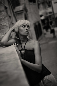 古城街道背景下的年轻女性吸烟香烟肖像。