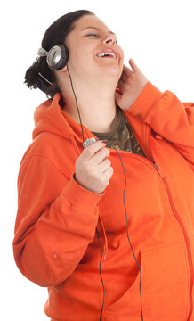 胖的年輕女子在橙色運動衫，頭戴式耳機和MP3播放器
