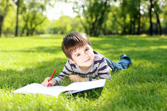 一個(gè)男孩在公園里拿著一本書(shū)的肖像