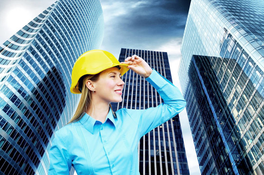 站在建筑物背景上的年輕建筑師女士戴著防護頭盔