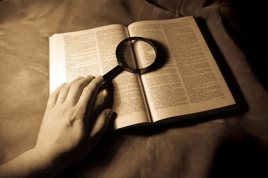 放大鏡；書和人的手。