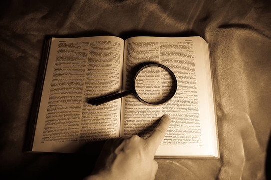 放大鏡；書和人的手。