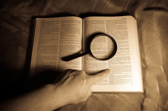 放大鏡；書和人的手。