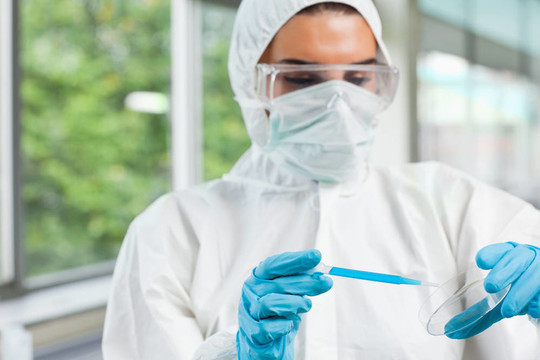 保护女性的理科学生在实验室培养皿中滴蓝色液体