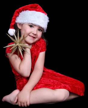 漂亮的小女孩在Santa戴著金色的帽子。孤立的黑色