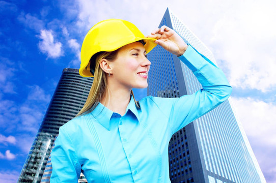 站在建筑物背景上的年輕建筑師女士戴著防護(hù)頭盔