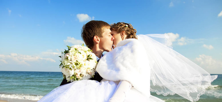 新婚夫婦在海灘上接吻。