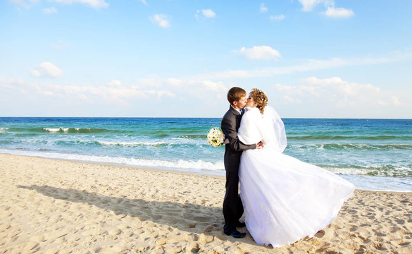 新婚夫婦在海灘上接吻。