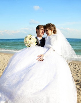 新婚夫婦在海灘上接吻。