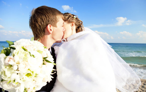 新婚夫婦在海灘上接吻。