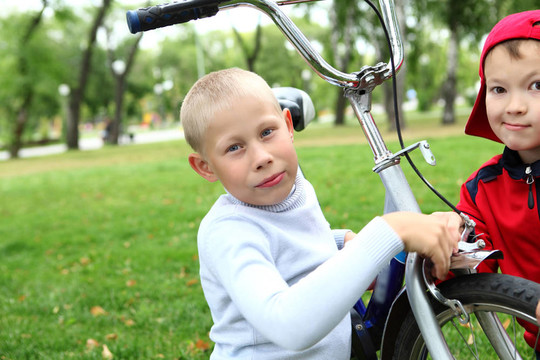 在绿色公园里骑自行车的男孩