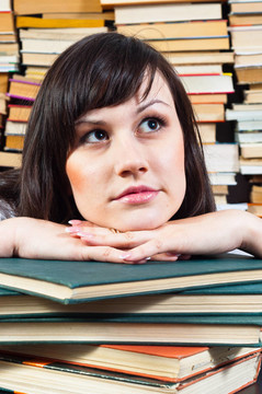 年輕的學(xué)生女孩在書上做白日夢