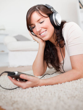 迷人的黑發(fā)女人的MP3播放器聽音樂，趴在客廳的地毯
