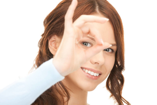 可愛的女人透過手指看洞