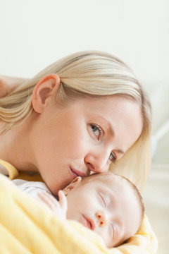 可愛的母親吻著她熟睡的嬰兒