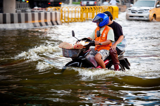 兩個(gè)騎摩托車的人在洪水中航行
