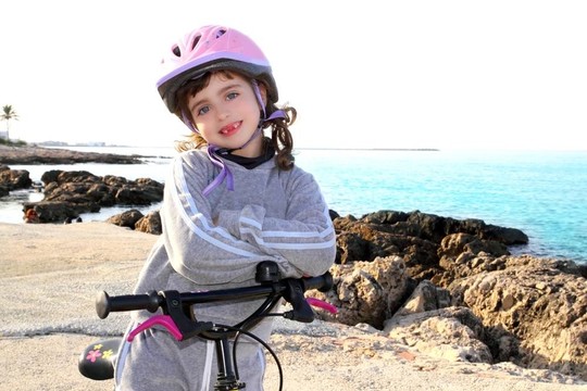 小女孩快乐的粉红色头盔在岩石海