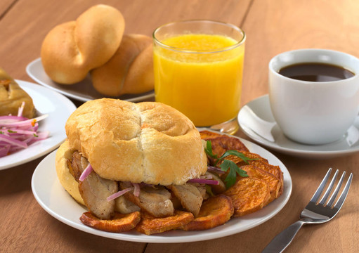 典型的秘魯早餐包括Pan con Chicharron（BUN炒肉）和油炸紅薯；塔瑪爾（左）；莎莎女