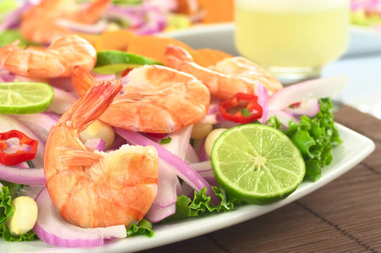 秘魯ceviche大蝦；紅洋蔥；石灰；熟玉米粒和辣椒在秘魯?shù)碾u尾酒叫皮斯科酸對(duì)生菜（選擇性聚焦在第一