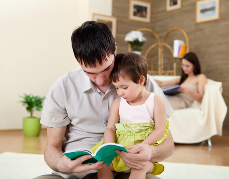 年輕的父親讀一本書給他的女兒