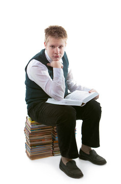 穿著校服的男生坐在一包書上，手里拿著打開的書