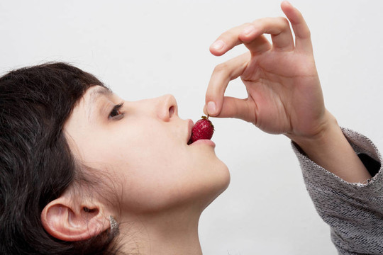 女性口腔中美味草莓的圖像--白色分離