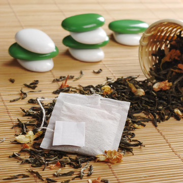 袋泡茶空白標(biāo)簽失去綠茶干茉莉花和一個(gè)木制的濾茶器和后臺(tái)的一些白色和綠色的石頭（選擇性焦點(diǎn)；關(guān)注袋泡茶