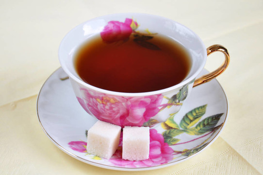 在白色背景下隔離的一杯茶和糖