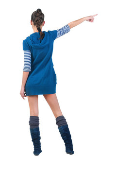 美麗的年輕女子在衣服指著墻壁。后視圖。