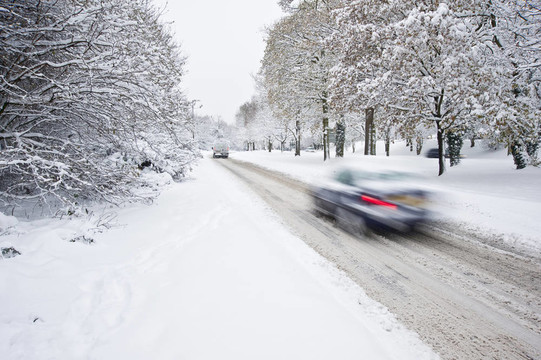道路上的深冬季積雪與模糊移動汽車