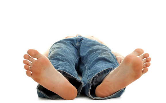 無法識別的年輕光著腳的人躺在地板上