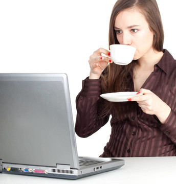 年輕的棕色頭發(fā)的女人用筆記本電腦和一杯熱的東西