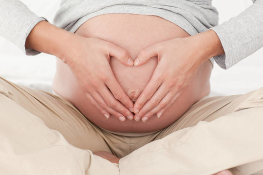 一個孕婦在她肚子上做心臟標志
